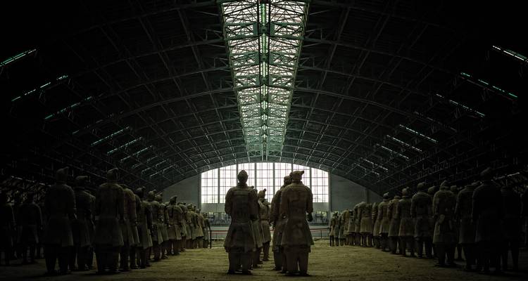 Silhouetted ranks of the Terracotta Army stand beneath the vast arched roof of their excavation hall.