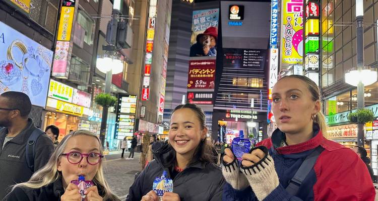 Eine Gruppe junger Frauen steht in einem belebten Stadtgebiet.