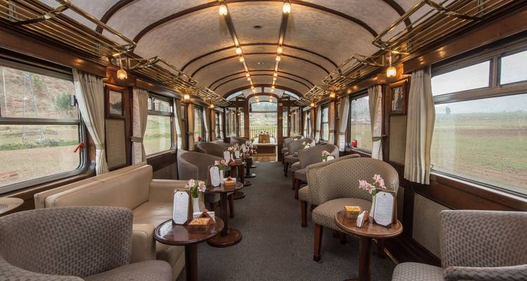 Interior lujoso de un vagón de tren preparado para cenar.