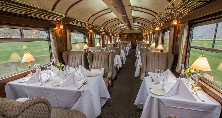 Interior de un lujoso vagón comedor de tren preparado para el servicio de comidas.