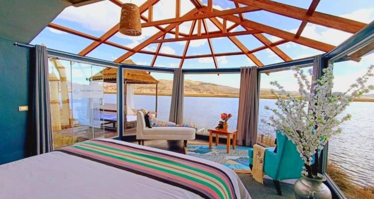Interior of a glass-roofed accommodation overlooking a lake.