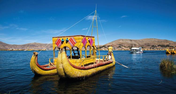 Decorative reed boat on a lake with hills in the background.