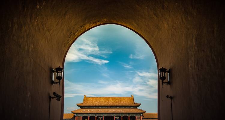 Een zicht door een gewelfde doorgang naar een traditioneel Chinees gebouw.