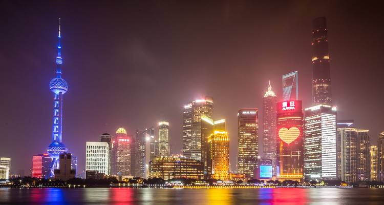 Los coloridos reflejos de las luces en el río Huangpu mientras el horizonte de Shanghai brilla de noche