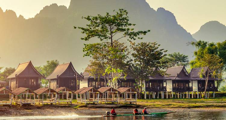 Resort junto a un río con montañas de fondo.