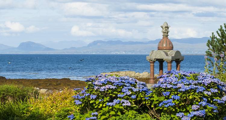 Decorative monument with blue flowers by the sea.