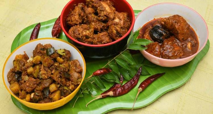 Traditional Indian dishes served in bowls on a green tray with chilies.