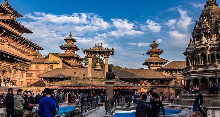 Des gens marchant dans une cour animée entourée d'architecture traditionnelle.