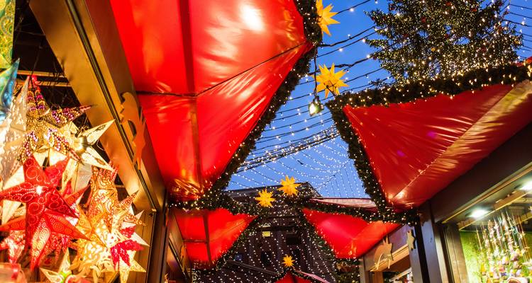 Une scène animée de marché de Noël avec de nombreuses lumières décoratives et étoiles.