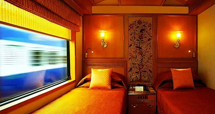 Cabine de train de luxe avec deux lits et décoration ornée.