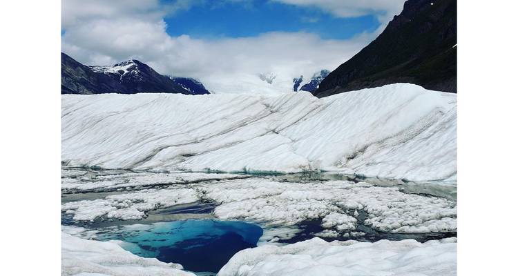 Glacier with ice formations and a small water pool.