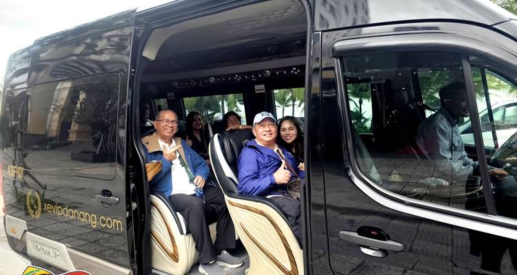 Los viajeros se sientan dentro de una furgoneta negra de turismo con la puerta lateral abierta.
