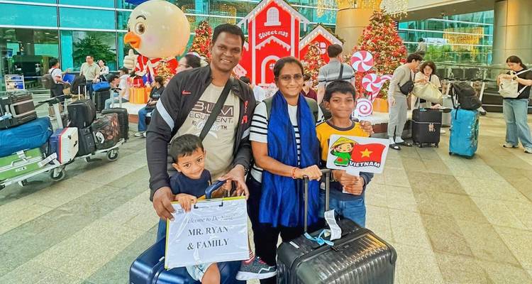 Familia con equipaje hace una pausa en una sala de llegadas del aeropuerto decorada para Navidad.