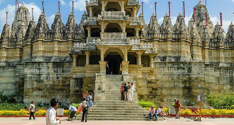 Templo de piedra intrincado con visitantes en la entrada, posiblemente en Ranakpur.