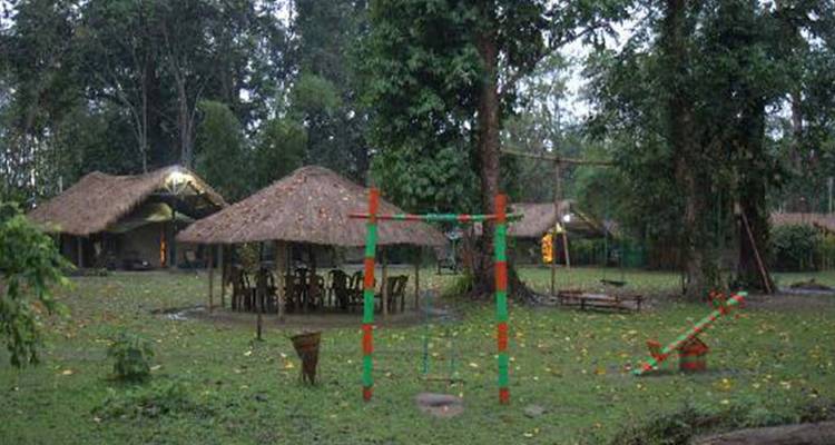 Zone extérieure avec des abris en bois simples et une verdure clairsemée.