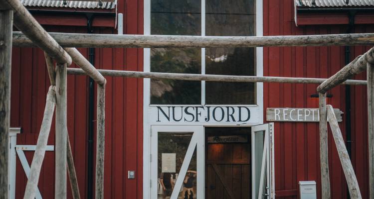 Red building with a 'Nusfjord Reception' sign.