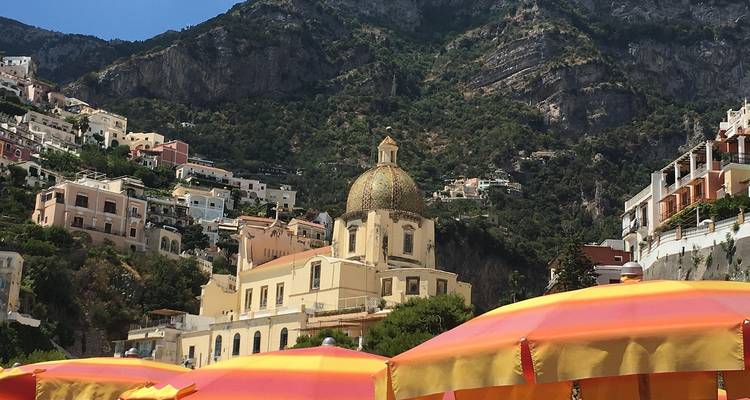 Ville côtière avec église à dôme et parasols de plage.