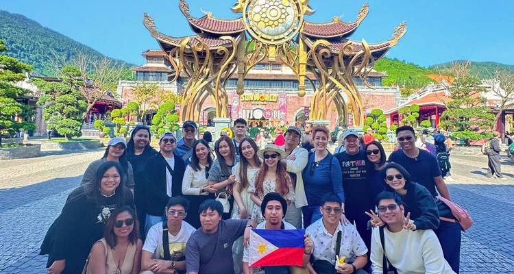 Grote groep poserend voor een ingewikkelde constructie, met een Filipijnse vlag.