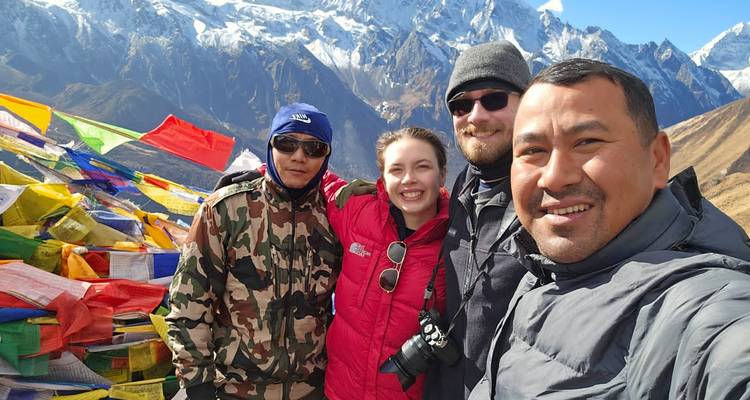 Randonneurs avec drapeaux de prière et montagnes en arrière-plan.