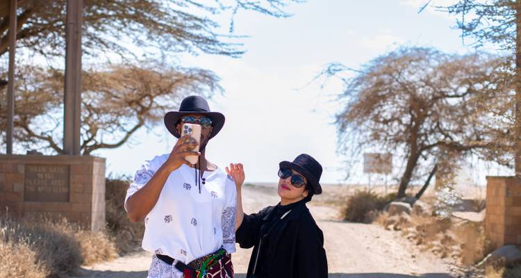 Deux touristes prenant un selfie avec des arbres de savane en arrière-plan.