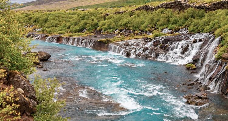 Waterfall flowing into a vibrant blue river.