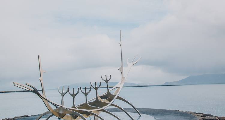 Metal sculpture resembling a boat by the waterfront.