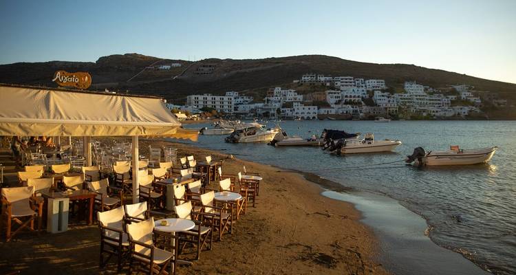 Empty beachfront cafe with boats in the shallow water.