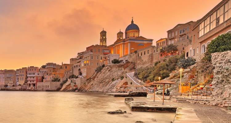 Coastal cityscape with well-lit historical buildings during sunset.
