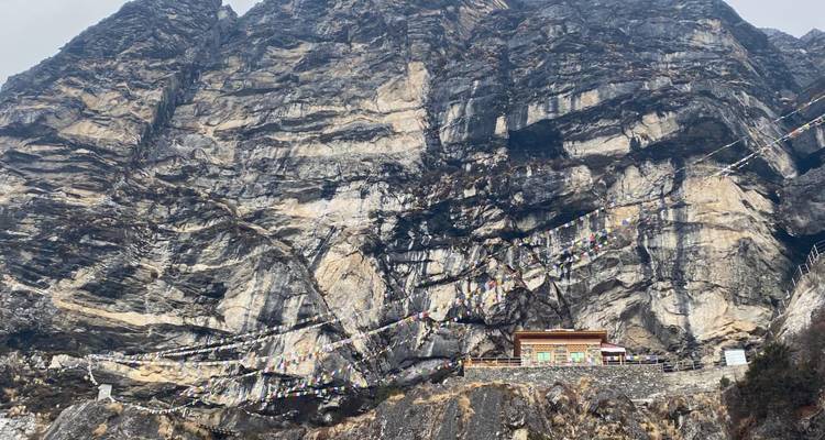 Falaise avec un petit bâtiment orné de drapeaux de prière.