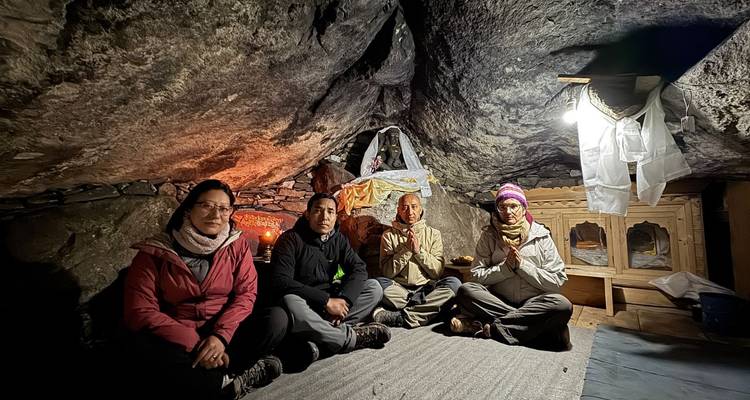 Un groupe de quatre personnes assises à l'intérieur d'un espace semblable à une grotte avec un petit sanctuaire.