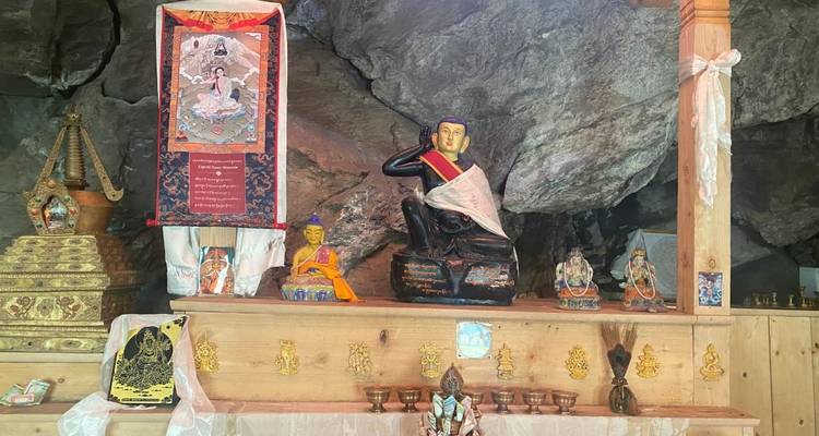 Une collection de statues religieuses et d'objets décoratifs sur une étagère à l'intérieur d'une grotte.