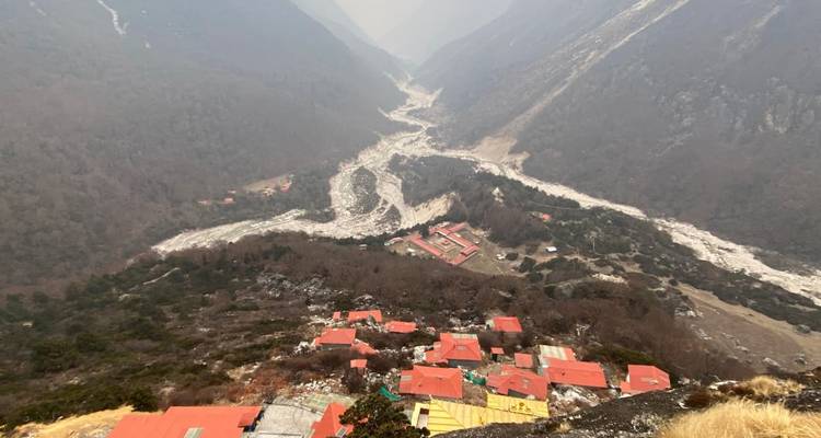 Vue aérienne d'une vallée avec une rivière serpentine et des bâtiments aux toits rouges.