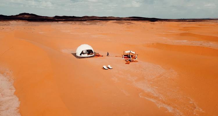 Dome tent in the center of a vast desert landscape.