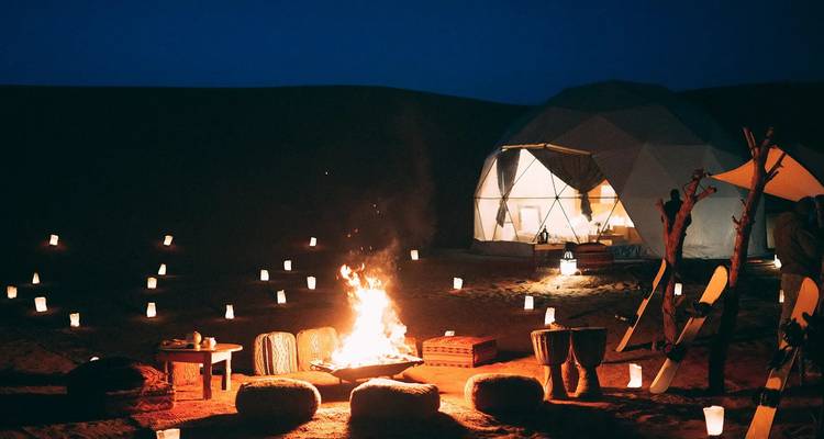 Campsite at dusk with a campfire and lanterns creating a warm ambiance.