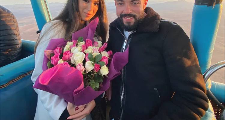 Couple with a bouquet of roses in a hot air balloon.