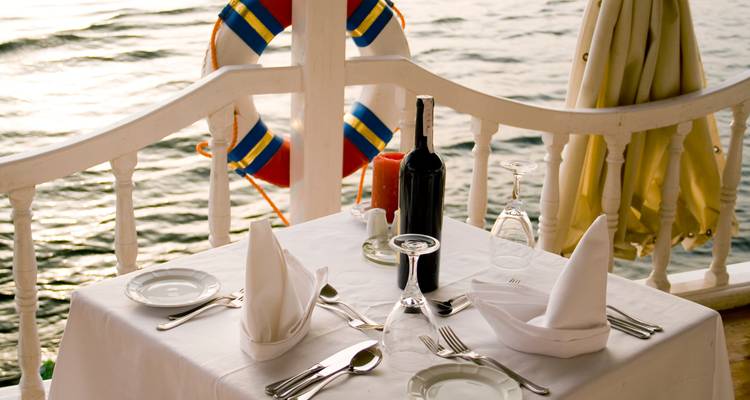 Een eettafel gedekt voor twee, met uitzicht op het water.