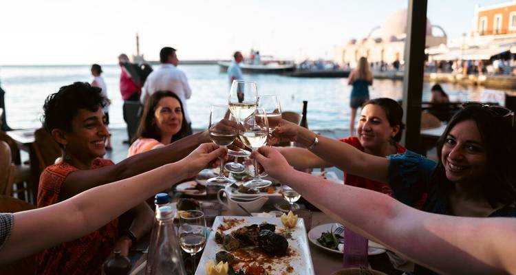 Group of friends toasting glasses at a marina restaurant.