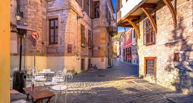 Charmante rue vide avec des bâtiments historiques colorés et des chaises en fer forgé.