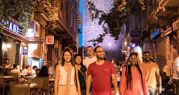 Groupe de personnes profitant d'une soirée dans une rue animée avec une architecture historique.