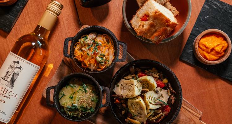 A selection of gourmet dishes and a bottle of wine presented on a wooden table.