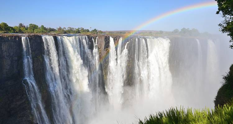 Victoria Falls cascading with a rainbow arcing above the mist.