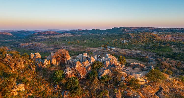Rocky outcrops overlooking a vast landscape during sunset.