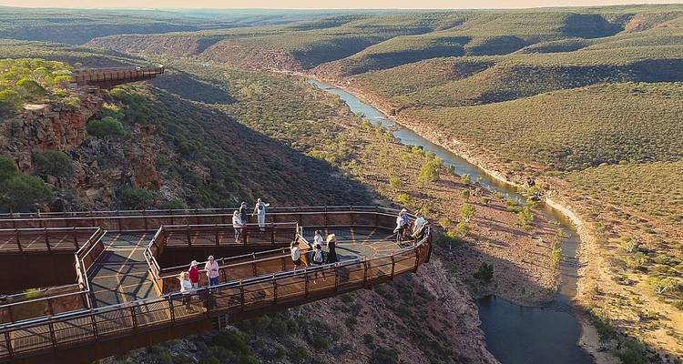A scenic lookout with people enjoying a panoramic view over a canyon and river.