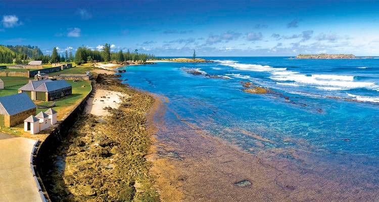 Una hermosa vista costera con agua cristalina y estructuras históricas en la Isla Norfolk.