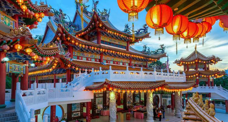 Temple asiatique coloré et complexe avec des lanternes suspendues au crépuscule.