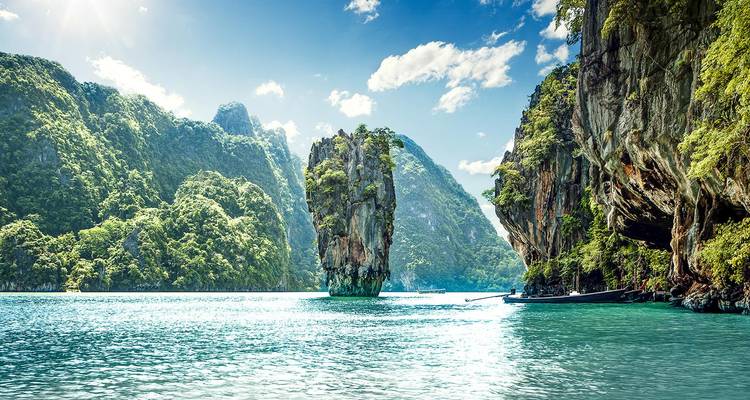 Tall karst limestone formation surrounded by turquoise water.