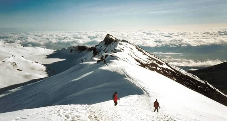 Crêtes montagneuses couvertes de neige, ciel et nuages à l'horizon.