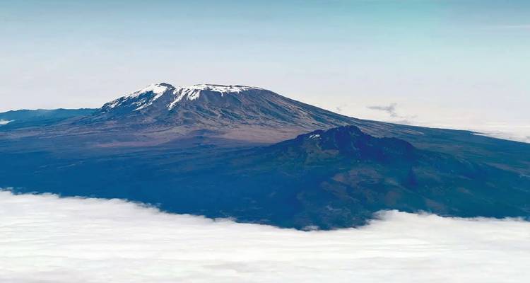 Sommet enneigé distant au-dessus d'une couche de nuages, vue panoramique.