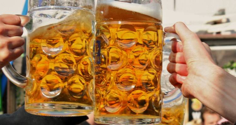 Des gens qui trinquent avec des chopes de bière à l'extérieur.