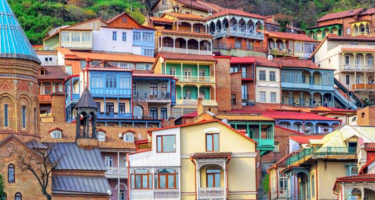Maisons colorées à flanc de colline avec balcons dans un cadre urbain historique.